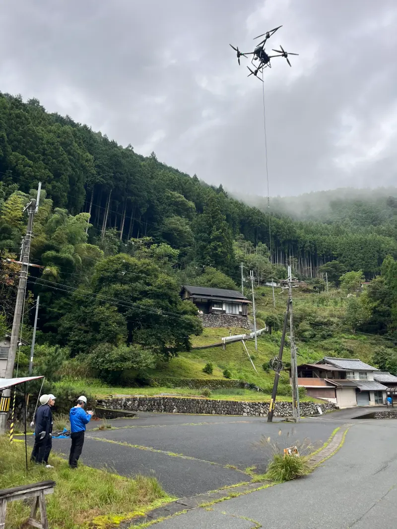 山あいの集落で、ヘルメット姿のスタッフがFlyCart 30を操縦する様子
